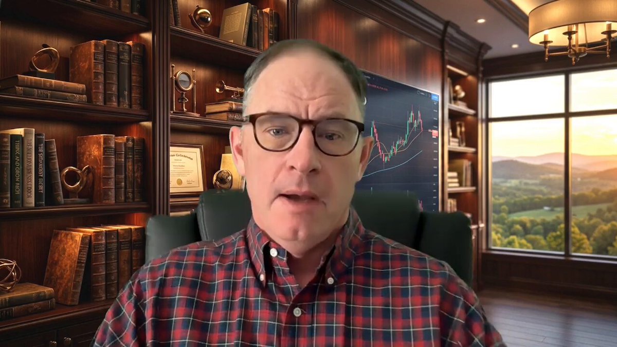 The image shows a man wearing glasses sitting behind a desk with a window, looking at the camera. He appears to be giving a presentation or speech about something related to cryptocurrency. The background features bookshelves filled with various books, suggesting that he might be an expert in the field of finance or investing.
