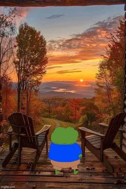 A frog character in a blue shirt stands on a wooden porch between two Adirondack chairs, watching a stunning autumn sunset over rolling mountains. The peaceful "Gm" (good morning) post reflects the calm, awe-inspiring morning scene of vibrant fall foliage and golden skies.