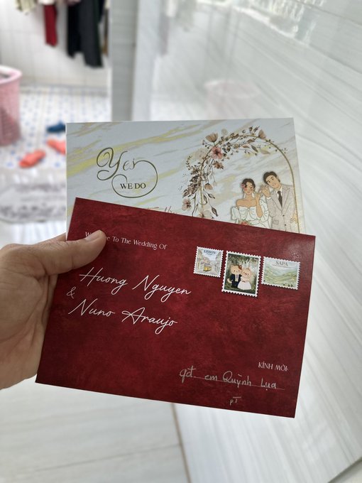 A hand holds two wedding invitation cards—one featuring an illustrated couple under a floral arch with "Yes We Do" in elegant script, and the other a deep burgundy envelope-style invitation addressed to "Huong Nguyen & Nuno Araujo" with postage stamps, dated "13." The post humorously captures the dilemma of choosing between two beautiful designs for the wedding invites.