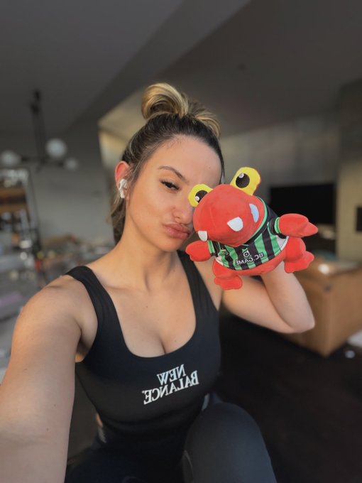 A woman takes a selfie while puckering up next to a red plush mascot wearing a green jersey that reads "BLACK CLAWS," referencing the $BC ticker from the GM post.