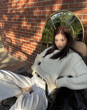A woman in a cream sweater sits relaxed in a chair against a brick wall, with no visible text or branding. The post's reference to "samo" (likely a style, brand, or personal association) connects to her aesthetic look, though no specific product or label is shown to tie directly to the caption.