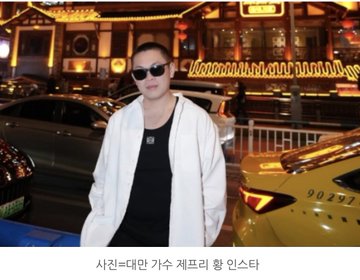 A man wearing sunglasses and a white hoodie stands in front of a taxi with the caption "사친=대만 가수 채프리 황 인스타" (meaning "Insta of Taiwanese singer Jeffrey Hwang with a fan"). The image relates to the post, which discusses Jeffrey Hwang's unfortunate experience in the cryptocurrency market, including purchasing an NFT and subsequently being liquidated on a long Ethereum position.