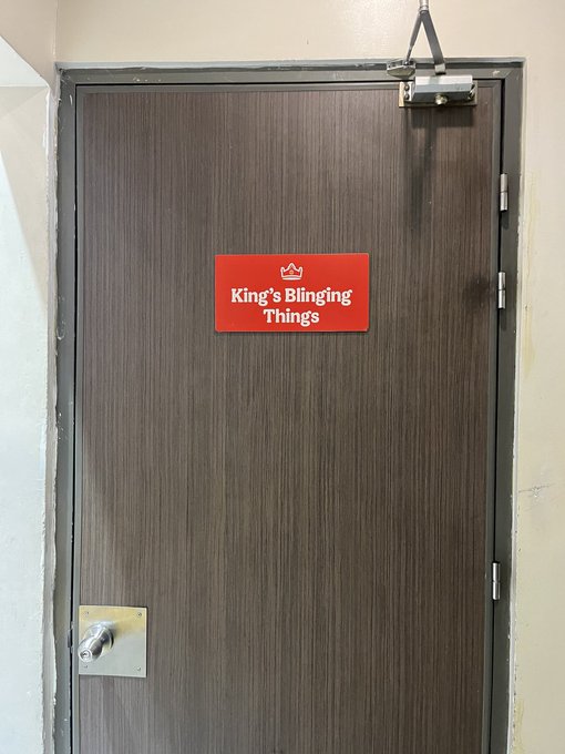 A dark wooden door features a small red sign reading 'King's Blinging Things' with a crown icon.