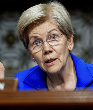 Senator Elizabeth Warren, wearing glasses and a blue blazer, speaks during what appears to be a Senate hearing, advocating for President Trump to disclose his 2026 crypto earnings ahead of the standard May 2027 filing deadline as the Senate prepares to debate the CLARITY Act.