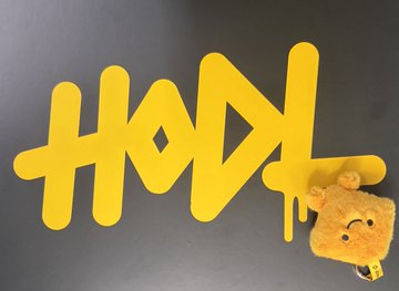 A yellow "HODL" logo with dripping paint effect next to a small yellow plush character on a gray background.