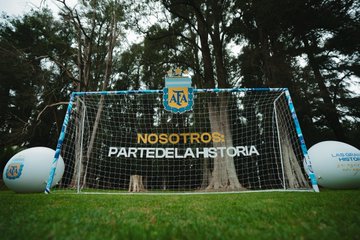 A soccer goal net displays 'AFA NOSOTROS PARTE DE LA HISTORIA' with the Argentine Football Association crest, set outdoors on grass.