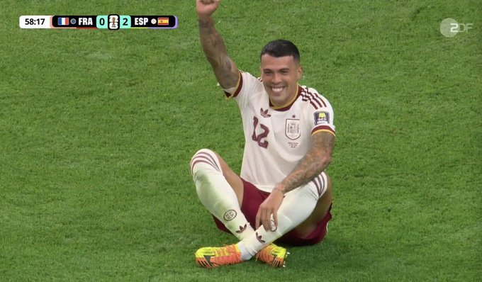Venezuelan player Jefferson Soteldo, wearing the white #12 Venezuela jersey, sits on the grass with his arm raised in celebration during a match against France, with the scoreboard showing Spain leading 0-2 at 58:17. Note: The image actually depicts Venezuela vs. France, not Spain, contradicting the post's claim of Spain leading 2-0.