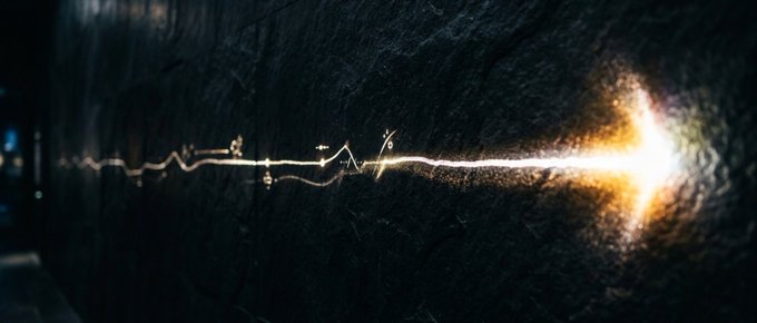 A glowing, crack-like line of bright light emerges from a rough, dark stone wall, resembling an electric or fiery fissure running horizontally across the surface.