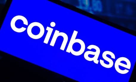 The image shows the Coinbase logo displayed in white text on a blue background, likely on a screen or digital display. The image reinforces the post's message about Coinbase's expansion efforts, as the company's branding visually anchors the news about its new U.K. regulatory authorization and its move into traditional finance offerings like perpetual futures and equities trading.
