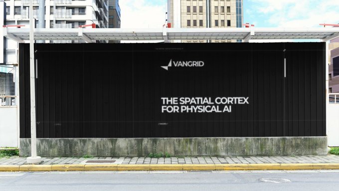 A black billboard or container displaying the text 'VANGRID' with a logo and the tagline 'THE SPATIAL CORTEX FOR PHYSICAL AI' against a city backdrop.