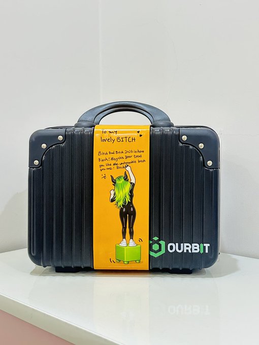 A small black briefcase with a yellow label reading 'To my lovely BITCH' and the OURBIT logo.
