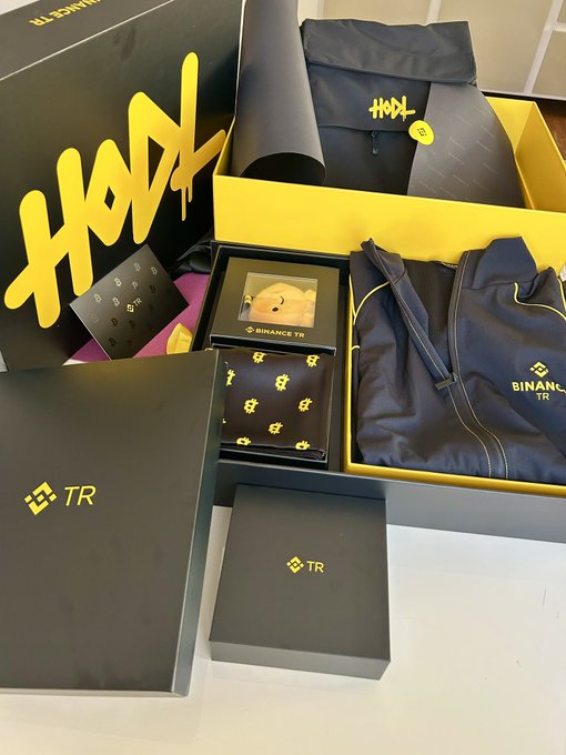 The image showcases an elegantly curated Binance TR branded gift package featuring a black and yellow color scheme, including a HODL-branded sleeve, a Binance TR vest/backpack, a decorative box with a Bitcoin plushie, and accessory boxes with the TR logo. This ties directly to the post thanking the Binance TR team for their thoughtful gifts and HODL Health message, with the promotional merchandise and branded packaging reflecting the company's crypto-themed branding and appreciation gesture.