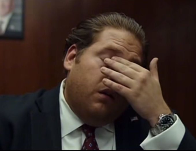 A man in a dark suit and red tie rubs his eyes in a facepalm gesture, wearing a silver watch, appearing exasperated. The image illustrates frustration following the recent conclusion of the World Cup.