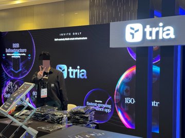 A person poses in front of a 'tria' branded display with the text 'INVITE ONLY' and 'The fast-growing pipeline start-up' visible at what appears to be a trade show or conference booth.