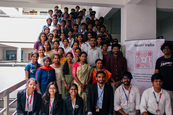 A large group photo of people gathered around a banner that reads 'team india' with a QR code, appearing to be at a tech or community event.