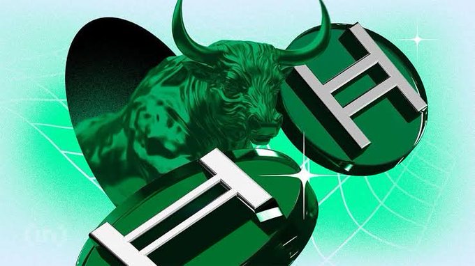 A stylized digital artwork features a green bull's head flanked by two circular discs displaying the letter "H," set against a light teal background with sparkle effects.