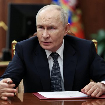 A portrait of Russian President Vladimir Putin sitting at a desk, illustrating news regarding his signing of legislation to regulate digital assets and investor rights.