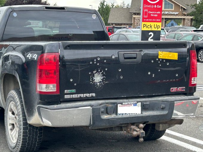 A black GMC Sierra pickup truck is parked in a parking lot near a "Drive Up & Go Pick Up 2" sign, with numerous bullet holes peppered across its tailgate, a Washington "Northwest" license plate, and a "$8" sticker visible. The bullet-riddled truck serves as a visual metaphor for the post's boast about "aping" a low-cap crypto coin ($DOGEBRIDE) and watching it "rip" to a 7x return while others were "sleeping"—much like firing blindly into a target, the trader took a risky shot at a volatile micro-cap coin and hit a winner.