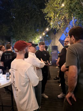 A nighttime outdoor gathering with several people standing together under string lights.