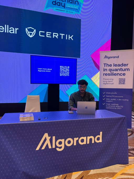 A man sitting at an Algorand booth at a 'Chain Day' conference, with signage highlighting Algorand as 'The leader in quantum resilience' and mentions of Certik.