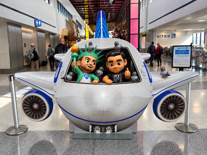 A creative airplane sculpture displayed in an airport terminal featuring cartoonish figures of the Statue of Liberty and a man in an NY shirt, with pigeons perched on top and United Airlines signage visible in the background.