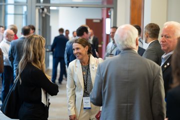 A networking event with professionals in business attire conversing in a brightly lit indoor space.
