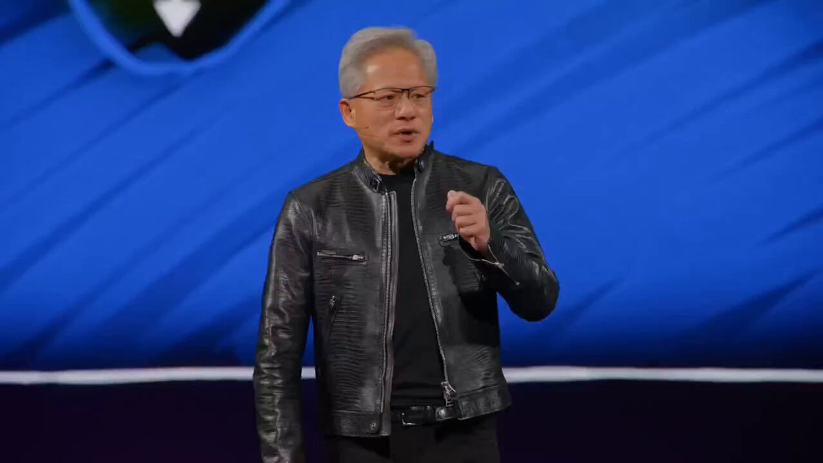 The image features a man wearing a black leather jacket, standing on stage with his hands up as if he's giving a speech or presentation. The background of the image shows a blue wall, which could be part of an event setup for the speaker. The caption at the bottom of the image reads "$CRWV $NBIS 儿子们，开心了 Vera Rubin全面投产，能率先拿到货的AI小云厂最收益了", which suggests that the man is a speaker or presenter at an event related to artificial intelligence, specifically focusing on the work of Vera Rubin.

The image also contains some text elements such as "$CRWV $NBIS 儿子们，开心了 Vera Rubin全面投产，能率先拿到货的AI小云厂最收益了", which could be part of the title or description of the image.