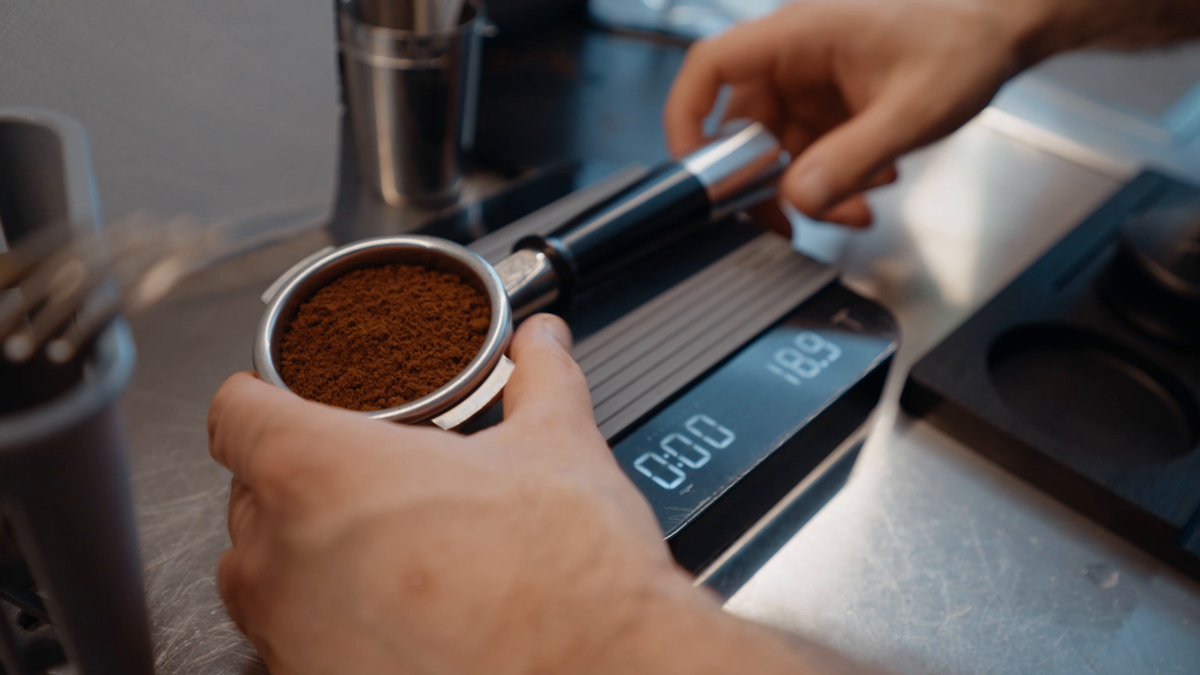 The image shows a person's hand holding a coffee cup filled with coffee beans or grounds, possibly making a purchase at a coffee shop using a mobile payment app like @WalletConnect Pay. The person appears to be preparing their order while paying for it. This scene highlights the convenience of modern technology and how it has transformed the way people make transactions in various settings, including coffee shops where customers can now pay with their smartphones or other mobile devices.