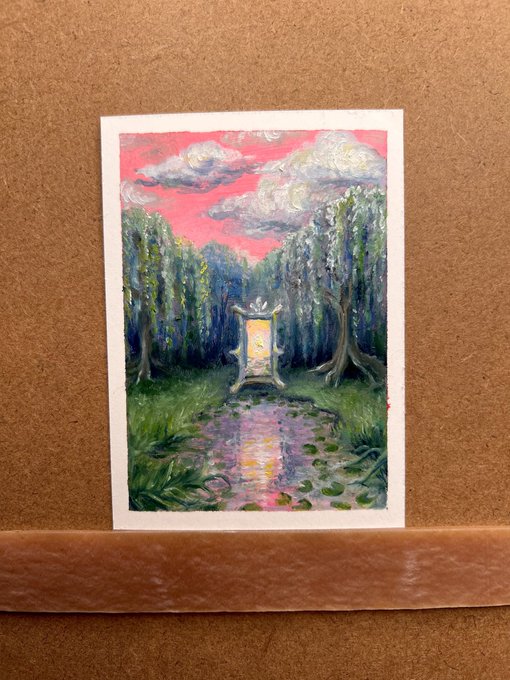 An impressionist-style painting on watercolor paper propped against a wooden ledge, depicting a serene landscape with a pink sky, clouds, trees framing a central pathway, lily pads, and an ornate archway or mirror in the distance.
