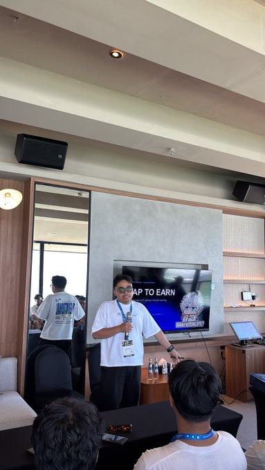 A speaker wearing a Coinfest lanyard and badge presents in front of a screen displaying "AP TO EARN" during Day 1 of Coinfest Asia, with attendees seated in the foreground. The setting appears to be a conference room where the speaker ran out of time to share additional insights about crypto earning opportunities.