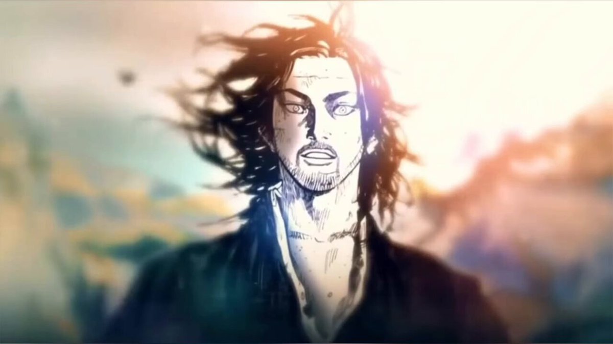The image features a man with long hair wearing a black outfit, possibly a robe or a kimono, standing against a backdrop of mountains. The man appears to be looking directly at the camera, giving off an intense and focused expression. The background is blurred, drawing attention to the main subject in the foreground.