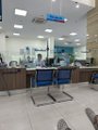 Photo of what appears to be an indoor service area or bank teller counter with glass partitions and blue signage visible above the counters.