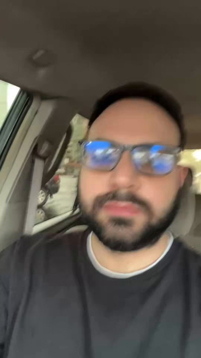 The image shows a man wearing glasses, sitting inside a car with his head tilted back as if he's looking out of the window or making a funny face for a photo. The man has a beard and appears to be wearing a black shirt. There is no visible text in the image, but it seems like there might be some sort of discussion or commentary about the Wallchain situation that led him to make this facial expression.