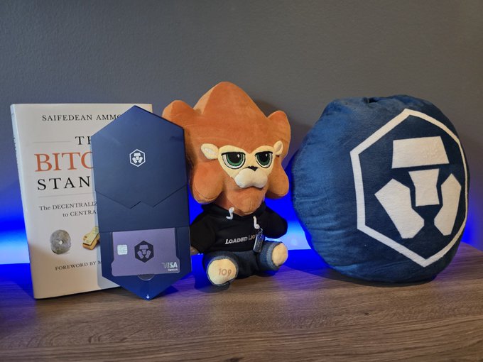 The image features a toy lion wearing sunglasses, sitting next to an advertisement for Bitcoin. The Bitcoin ad displays an eye-catching image of a large coin symbol with "CRO" written above it. This design aims to grab viewers' attention and promote the idea that cryptocurrencies are valuable in modern times.