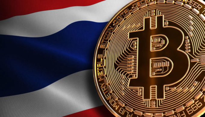 A physical Bitcoin coin in sharp focus against a backdrop of the Thai flag's red, white, and blue colors.