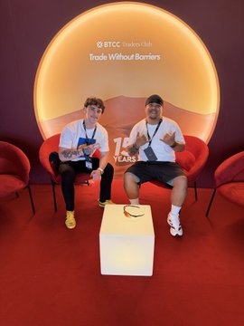 Two men sit in red chairs on a stage at a BTCC Traders Hub event, beneath a backdrop reading 'Trade Without Barriers' and '75 YEARS'.