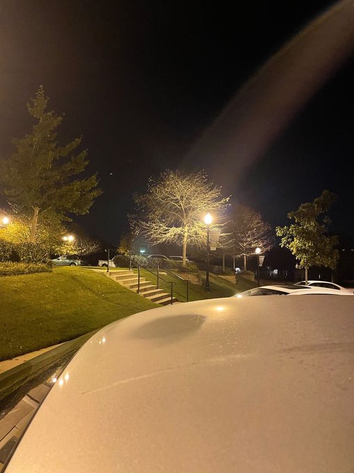 A white car's hood gleams under a nighttime scene of illuminated trees and street lamps along a quiet suburban sidewalk, capturing a peaceful "goodnight" moment after a long day on Crypto Twitter.