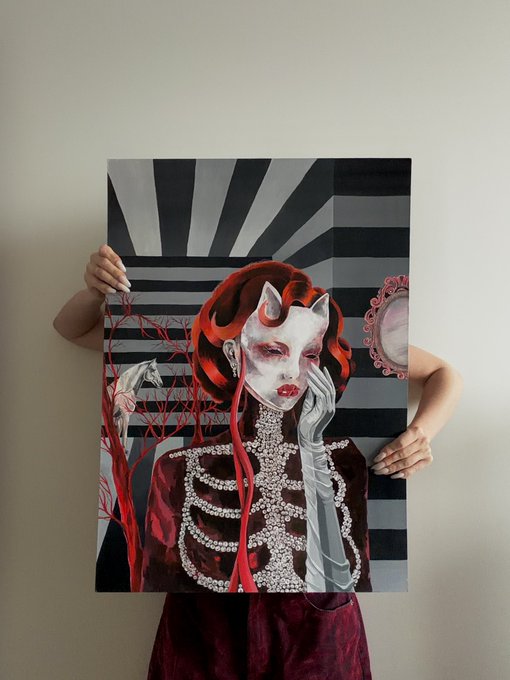 A person in dark red clothing holds up a large surreal canvas painting depicting a red-haired figure with a white fox mask, a silver-gloved hand, and skeletal/crystal detailing against a black and white striped background.