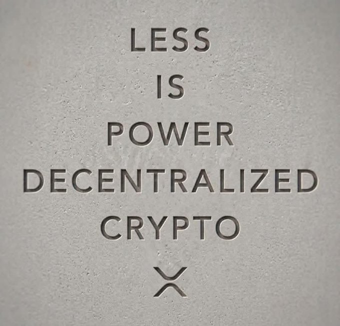 An engraved stone surface with the text 'LESS IS POWER DECENTRALIZED CRYPTO' and an XRP logo.