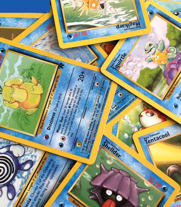 The image shows a collection of Pokemon cards scattered across a table or surface. The cards are predominantly blue and yellow, featuring various Pokemon characters such as Pikachu, Eevee, and others. Some cards have text written on them, while others do not. The cards appear to be in good condition, with no signs of damage or wear. The arrangement of the cards suggests that they might be a collection or a display for collectors to admire and organize by their characters or themes.