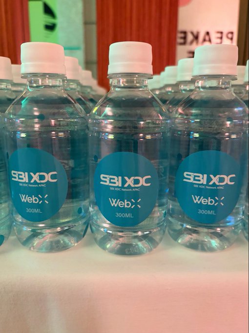 Several clear water bottles labeled 'SBIXDC 300ML' with the 'Web>' logo branded on blue circular labels.