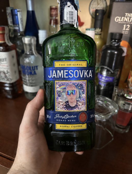 A hand holds a green 50cl bottle labeled "JAMESOVKA - THE ORIGINAL" with a photo of James (Jerry Becher) wearing sunglasses and "1827" branding, subtitled "Herbal Liquor" and "Monad Memes." The background shows a cluttered bar shelf with Absolut Vodka and Glenlivet 12 bottles. The image ties directly to the post's playful announcement of swapping coffee for the meme-themed "Jamesovka" spirit in support of the $JAMES token on Monad.