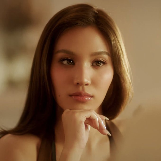 A confident woman rests her chin on her hand, gazing directly at the camera with a poised, contemplative expression. Her composed demeanor mirrors the provocative challenge of the post, embodying the calm before a competition of who will falter first.