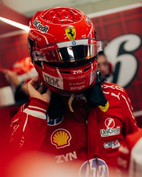 A Ferrari Formula 1 driver, dressed in a red racing suit adorned with sponsor logos including Shell, UniCredit, CEVA, Zyn, and IBM, adjusts his red helmet featuring the iconic Ferrari prancing horse and "Zyn" branding, preparing for qualifying at the Monza Grand Prix as part of the Scuderia Ferrari team in partnership with BingX.