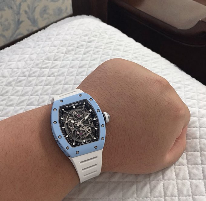 A close-up of a person's wrist wearing a blue and white Richard Mille skeleton dial watch.