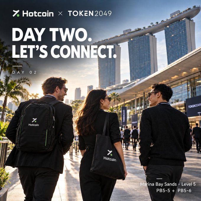 A promotional graphic for 'Hotcoin X TOKEN2049' featuring the text 'DAY TWO. LET'S CONNECT.' and showing three people walking toward Marina Bay Sands, with location details 'Marina Bay Sands · Level 5 PB5-5 + PB5-6' at the bottom.