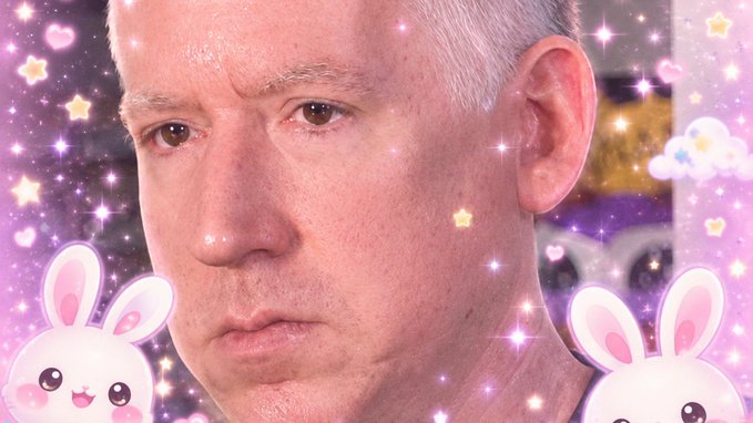 A close-up of a man's face surrounded by a pink and purple kawaii-style filter featuring sparkles, stars, and cartoon bunny characters.