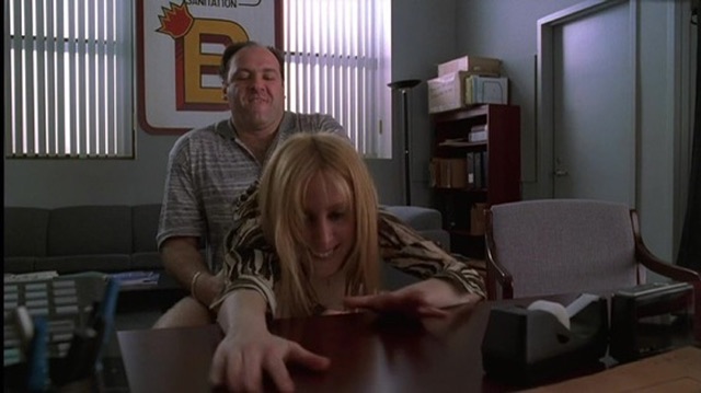 A man is playfully groping a laughing blonde woman at a desk, while a "Sanitation" sign with a large "E" is visible in the background. The image humorously juxtaposes with the "nobody: brian armstrong:" caption to depict an absurd or unprompted action, suggesting the man is the Coinbase CEO acting out of nowhere.