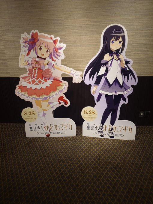 Two anime character standees (life-size cutouts) for the series '魔法少女まどか☆マギカ' (Puella Magi Madoka Magica) displayed on a carpeted floor, each marked with '8.28 (SUN) CLOSESHOW'.