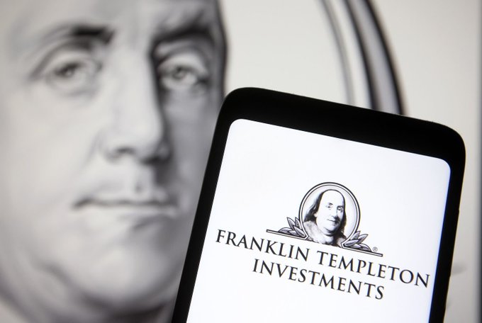 A black and white photograph showing Benjamin Franklin's face in the background with a smartphone displaying the Franklin Templeton Investments logo in the foreground.